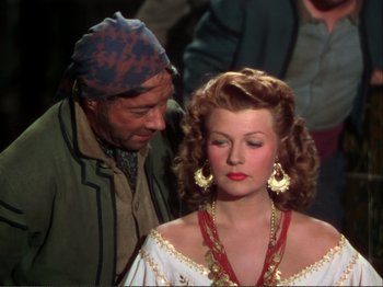 Movie still from “The Loves of Carmen” (1948), directed by Charles Vidor – An old man and a beautiful woman standing next to each other; Medium shot, Over the shoulder angle