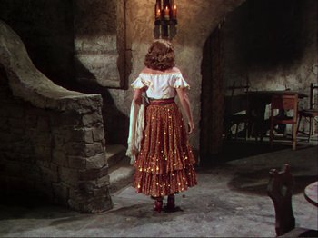Movie still from “The Loves of Carmen” (1948), directed by Charles Vidor – A woman in a red and white dress standing in a room; Wide shot, Low angle
