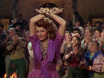 Movie still from “The Loves of Carmen” (1948), directed by Charles Vidor – A woman in a purple dress is dancing in front of a group of people; Medium shot, Low angle