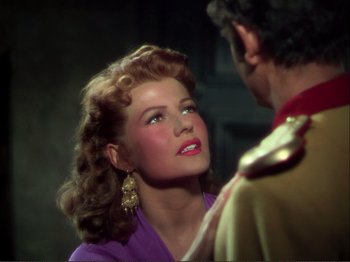 Movie still from “The Loves of Carmen” (1948), directed by Charles Vidor – A woman in a purple dress looking at a man in a red suit; Close Up shot, Over the shoulder angle