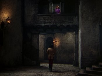 Movie still from “The Loves of Carmen” (1948), directed by Charles Vidor – A man standing in a room with a light in his hand; Wide shot, High angle