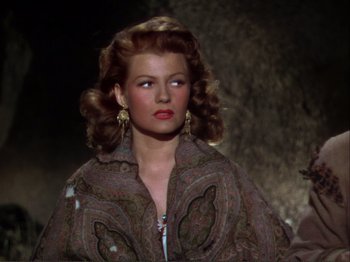 Movie still from “The Loves of Carmen” (1948), directed by Charles Vidor – A woman in a brown jacket and gold earrings; Close Up shot, Over the shoulder angle