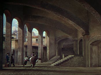 Movie still from “The Loves of Carmen” (1948), directed by Charles Vidor – Two people on a horse in an archway with stairs; Extreme Wide shot, High angle