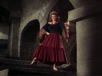 Movie still from “The Loves of Carmen” (1948), directed by Charles Vidor – A woman standing on some steps wearing a dress; Wide shot, Low angle