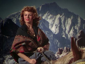 Movie still from “The Loves of Carmen” (1948), directed by Charles Vidor – A woman in a red and black cape riding a horse; Medium shot, Low angle