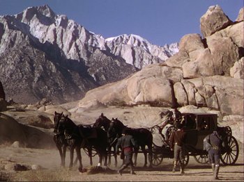 Movie still from “The Loves of Carmen” (1948), directed by Charles Vidor – A group of horses pulling a carriage down a dirt road; Extreme Wide shot, Low angle