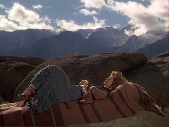 Movie still from “The Loves of Carmen” (1948), directed by Charles Vidor – A woman laying on top of a blanket on top of a hill; Wide shot, High angle