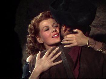 Movie still from “The Loves of Carmen” (1948), directed by Charles Vidor – A man and a woman embracing each other in a dark room; Medium shot, Overhead angle