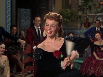 Movie still from “The Loves of Carmen” (1948), directed by Charles Vidor – A woman in a black dress is holding a vase; Medium shot, Low angle