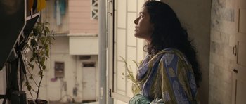 Movie still from “The Lunchbox” (2013), directed by Ritesh Batra – A woman looking out of a window with a plant in front of her face; Medium shot, Low angle