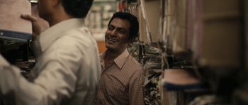 Movie still from “The Lunchbox” (2013), directed by Ritesh Batra – A man standing next to another man in a room; Medium shot, Over the shoulder angle