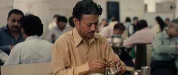 Movie still from “The Lunchbox” (2013), directed by Ritesh Batra – A man in a brown shirt is holding a bowl of food; Close Up shot, High angle