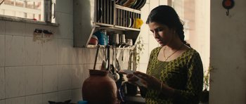 Movie still from “The Lunchbox” (2013), directed by Ritesh Batra – A woman in a kitchen looking at an item; Medium shot, Low angle