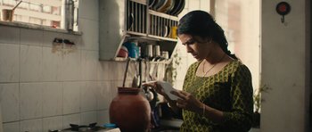 Movie still from “The Lunchbox” (2013), directed by Ritesh Batra – A woman in a kitchen looking at a paper; Medium shot, Low angle