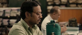 Movie still from “The Lunchbox” (2013), directed by Ritesh Batra – A person wearing glasses and a green bag; Close Up shot, High angle