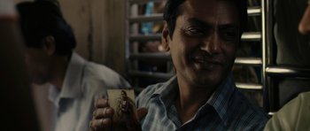 Movie still from “The Lunchbox” (2013), directed by Ritesh Batra – A man holding up a picture of a woman; Close Up shot, Over the shoulder angle