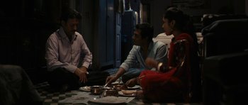Movie still from “The Lunchbox” (2013), directed by Ritesh Batra – A group of people sitting around a table with food on it; Medium shot, High angle