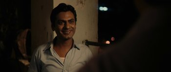 Movie still from “The Lunchbox” (2013), directed by Ritesh Batra – A man smiling for the camera in front of a wall; Close Up shot, Over the shoulder angle