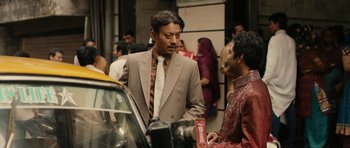 Movie still from “The Lunchbox” (2013), directed by Ritesh Batra – A man in a suit and tie standing next to another man in a suit; Medium shot, Over the shoulder angle