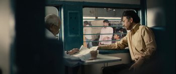 Movie still from “The Lunchbox” (2013), directed by Ritesh Batra – A man sitting at a table in front of a train; Medium shot, Over the shoulder angle