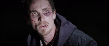 Movie still from “The Machinist” (2004), directed by Brad Anderson – A person with bruises on his face; Close Up shot, Over the shoulder angle