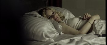 Movie still from “The Machinist” (2004), directed by Brad Anderson – A woman laying in a bed under a white blanket; Medium shot, High angle