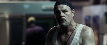 Movie still from “The Machinist” (2004), directed by Brad Anderson – An older man with a beard and a black hat; Close Up shot, Low angle