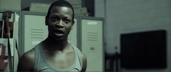 Movie still from “The Machinist” (2004), directed by Brad Anderson – A man in a tank top standing in front of two lockers in a room; Close Up shot, Over the shoulder angle