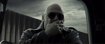 Movie still from “The Machinist” (2004), directed by Brad Anderson – A bald man wearing sunglasses and smoking a cigarette; Close Up shot, Low angle