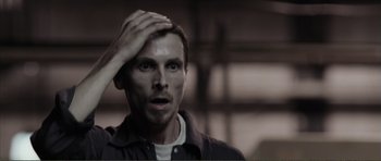 Movie still from “The Machinist” (2004), directed by Brad Anderson – A person holding his hand to his head; Close Up shot, High angle