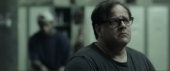 Movie still from “The Machinist” (2004), directed by Brad Anderson – A person wearing glasses and a black shirt; Close Up shot, Over the shoulder angle