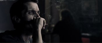 Movie still from “The Machinist” (2004), directed by Brad Anderson – A man is smoking a cigarette in a dark room; Close Up shot, Over the shoulder angle