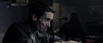 Movie still from “The Machinist” (2004), directed by Brad Anderson – A person sitting at a table with a glass of wine; Close Up shot, Over the shoulder angle