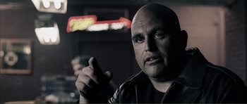 Movie still from “The Machinist” (2004), directed by Brad Anderson – A man with a bald head is pointing at the camera; Close Up shot, Over the shoulder angle