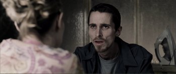 Movie still from “The Machinist” (2004), directed by Brad Anderson – A person in a room with another person; Close Up shot, Over the shoulder angle