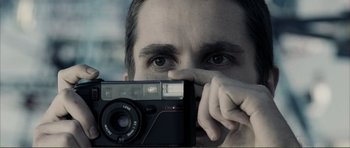 Movie still from “The Machinist” (2004), directed by Brad Anderson – A man is taking a picture with a camera; Extreme Close Up shot, Low angle