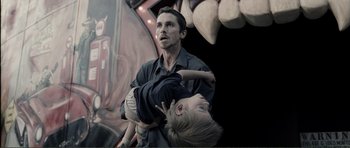 Movie still from “The Machinist” (2004), directed by Brad Anderson – A man holding a child in his arms; Medium shot, Low angle