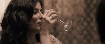 Movie still from “The Machinist” (2004), directed by Brad Anderson – A woman is drinking a glass of wine; Close Up shot, High angle