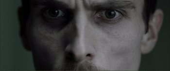 Movie still from “The Machinist” (2004), directed by Brad Anderson – A man's face with dark eyes; Extreme Close Up shot, Low angle