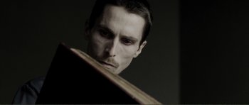 Movie still from “The Machinist” (2004), directed by Brad Anderson – A person looking at a book; Close Up shot, Low angle