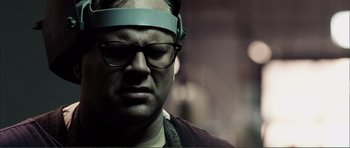 Movie still from “The Machinist” (2004), directed by Brad Anderson – A man with glasses and a head band on; Close Up shot, Low angle