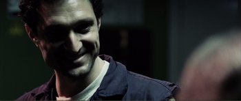 Movie still from “The Machinist” (2004), directed by Brad Anderson – A person smiling for the camera; Close Up shot, Over the shoulder angle