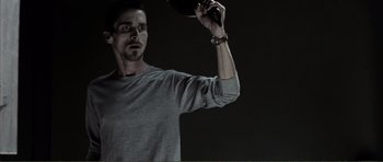 Movie still from “The Machinist” (2004), directed by Brad Anderson – A man holding a frisbee in his hand; Medium shot, Low angle