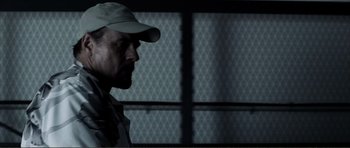 Movie still from “The Machinist” (2004), directed by Brad Anderson – A man wearing a baseball cap looking to his left; Close Up shot, Low angle