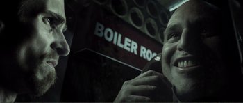 Movie still from “The Machinist” (2004), directed by Brad Anderson – A man talking on a cell phone in front of a boiler room sign; Close Up shot, Low angle