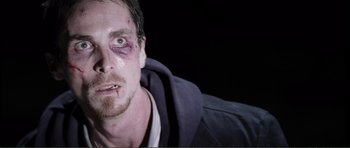 Movie still from “The Machinist” (2004), directed by Brad Anderson – A person with bruises on his face; Close Up shot, High angle