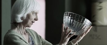 Movie still from “The Machinist” (2004), directed by Brad Anderson – An older woman is holding a glass bowl; Close Up shot, Low angle