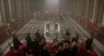 Movie still from “The Madness of King George” (1994), directed by Nicholas Hytner – A group of people sitting on chairs in front of a stage; Extreme Wide shot, High angle