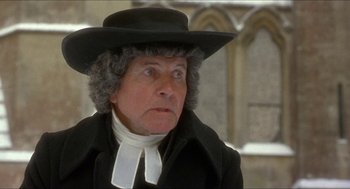Movie still from “The Madness of King George” (1994), directed by Nicholas Hytner – An older woman wearing a black hat and a black coat; Close Up shot, Over the shoulder angle