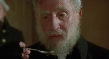 Movie still from “The Madness of King George” (1994), directed by Nicholas Hytner – An old man with a beard is holding a spoon in his mouth; Close Up shot, High angle